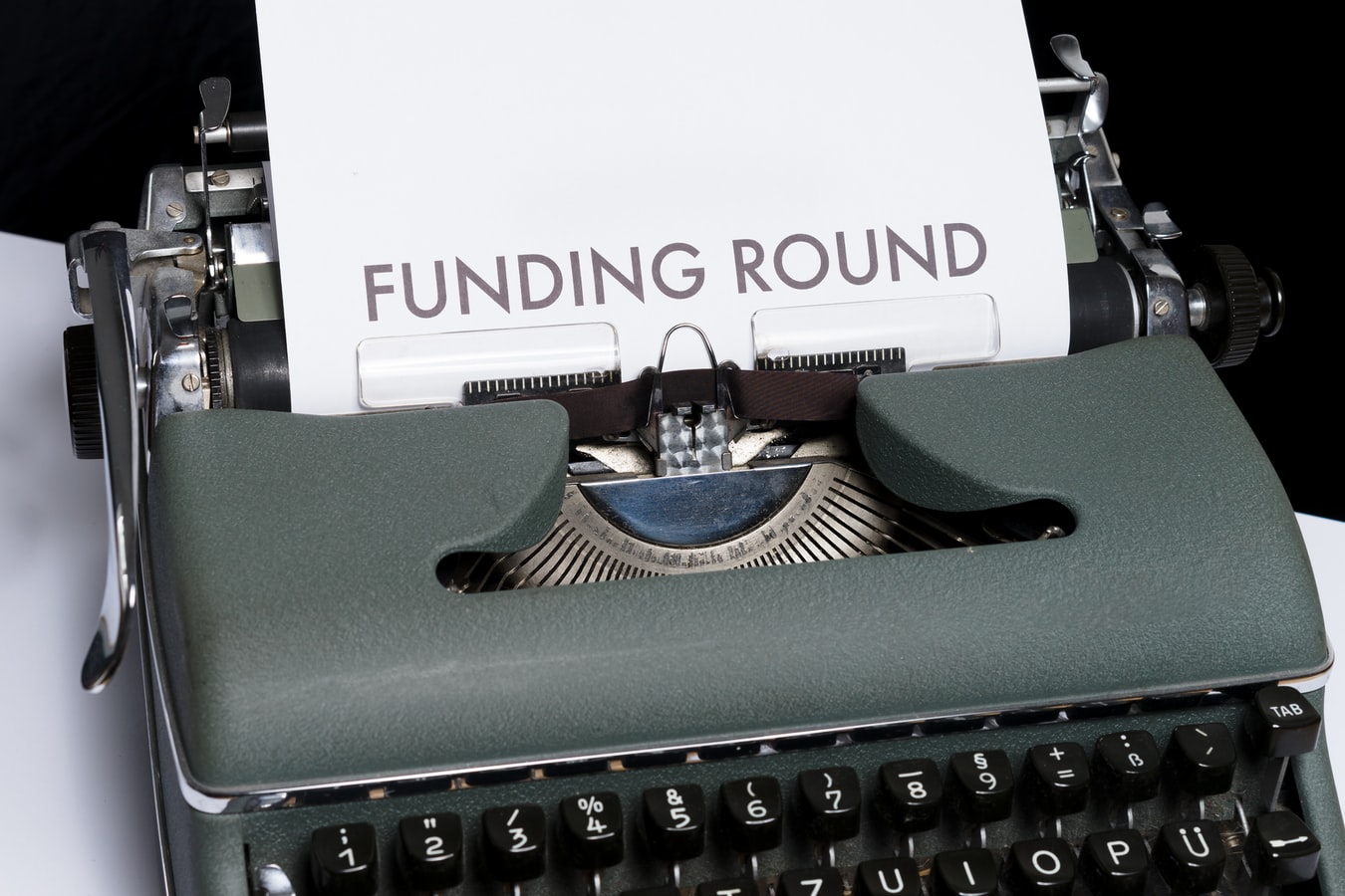 A typewriter with a piece of paper titled 'Funding Round' on it.