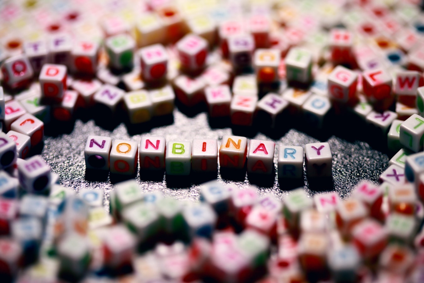 Nonbinary spelled out in tiny rainbow coloured letters.