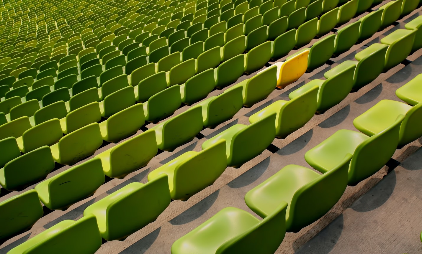 A lecture hall full of chairs, one is a different colour than the rest.